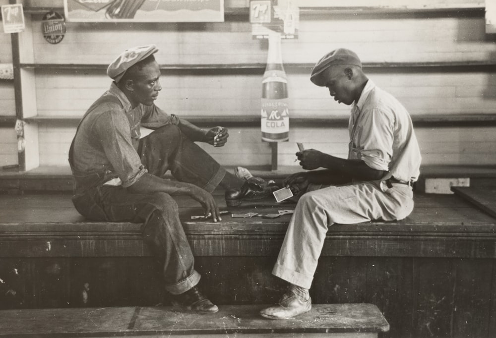 grayscale photo of two men sitting on bench