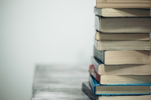 A stack of various books on a wooden table.