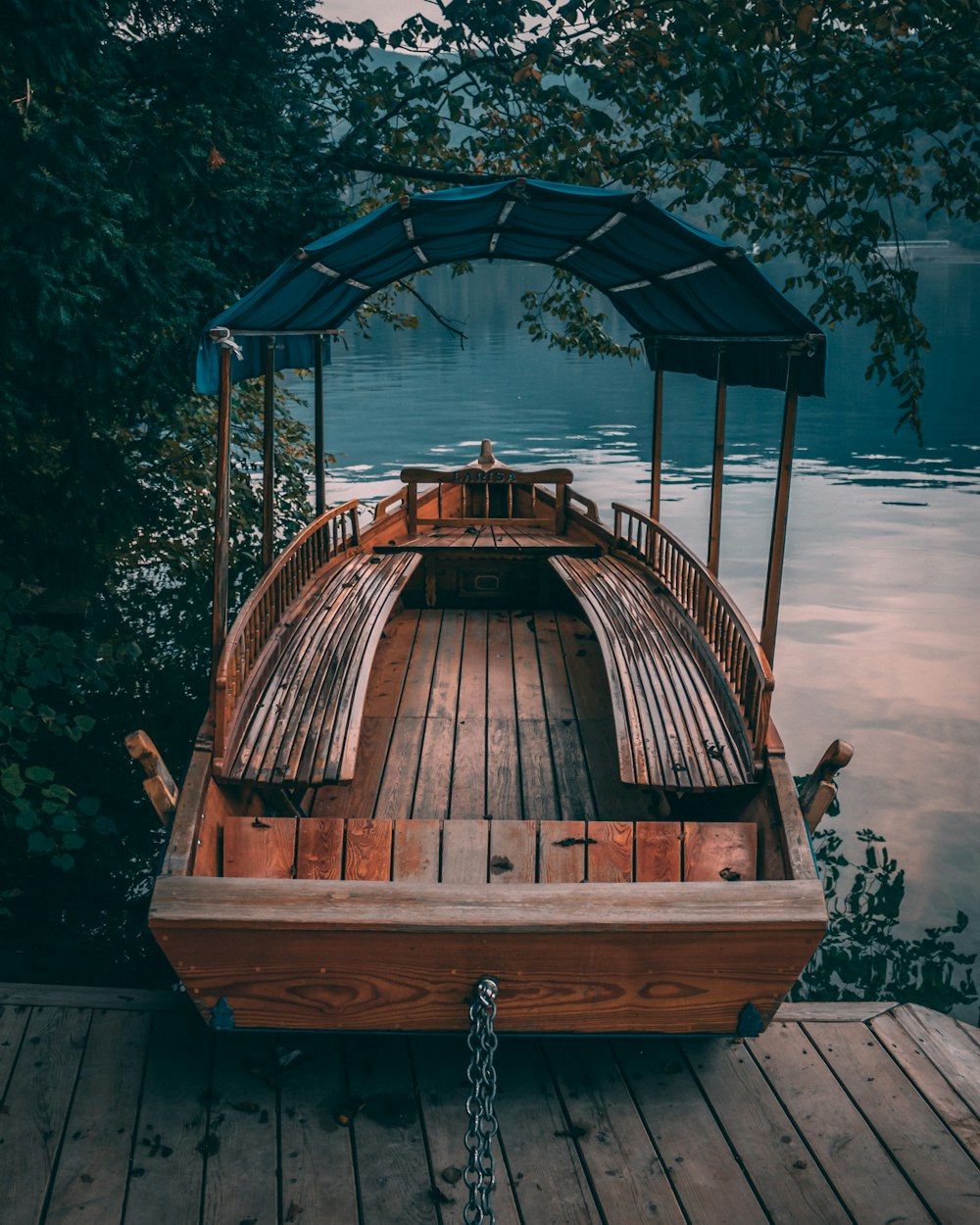 緑の木々に囲まれた水域と木製のドックの近くにある茶色の木製のボート