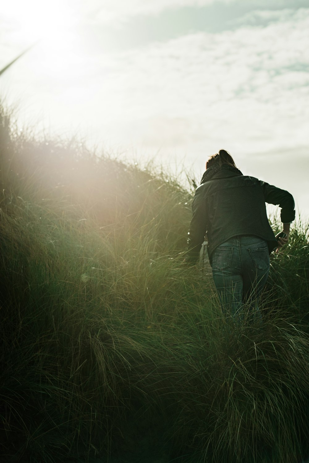Persona con chaqueta gris caminando en el campo de hierba