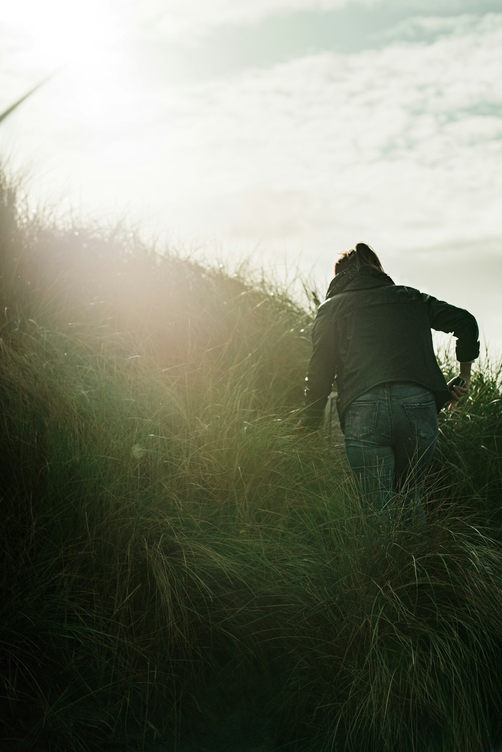 person wearing gray jacket walking on grass field