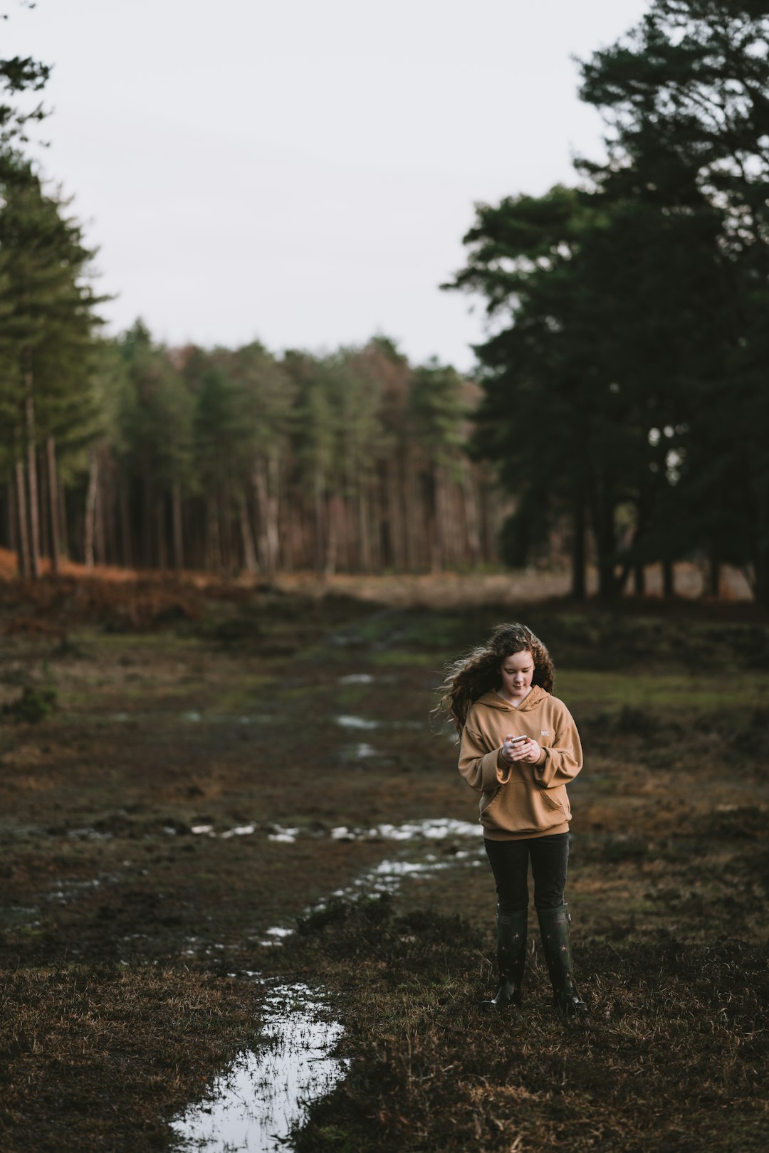 woman wearing brown coat standing on brown soil