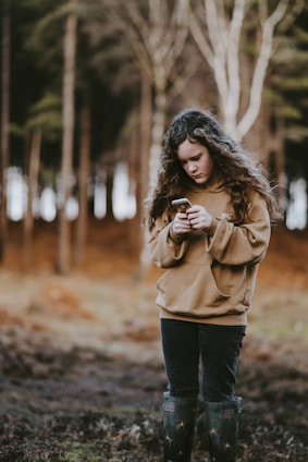 A young adult using the Quietshare app on their phone while hiking in a forest.