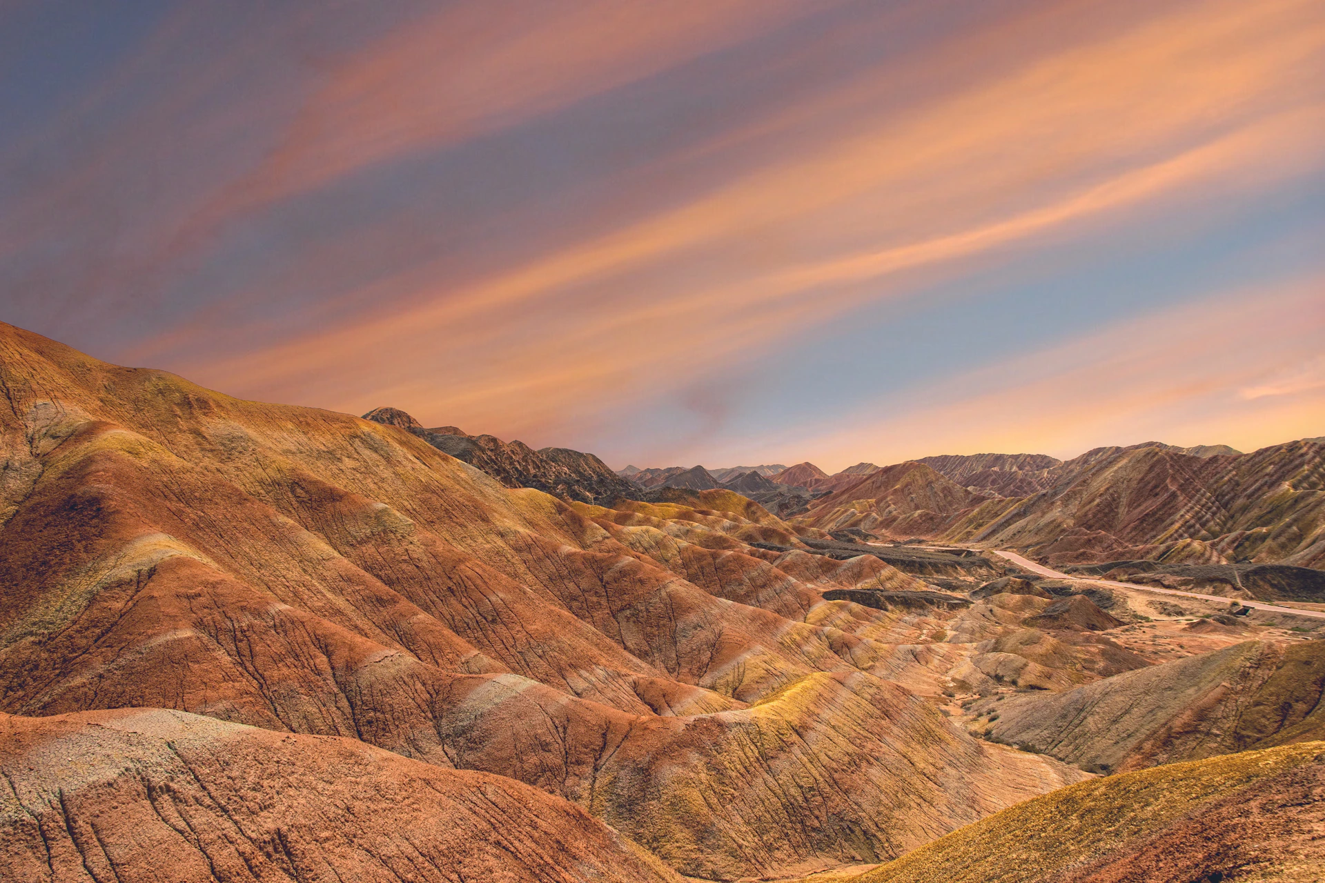 Colorful panoramic view of the Rainbow Mountain with hikers admiring the vibrant striped landscape.