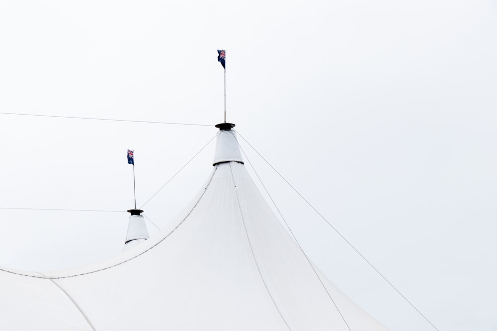 a large white tent with two flags on top of it