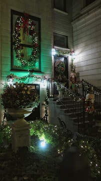 Smiling hosts welcoming guests at a decorated holiday home entrance.