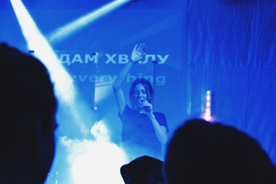 A singer holding a microphone on stage with sheet music in hand.