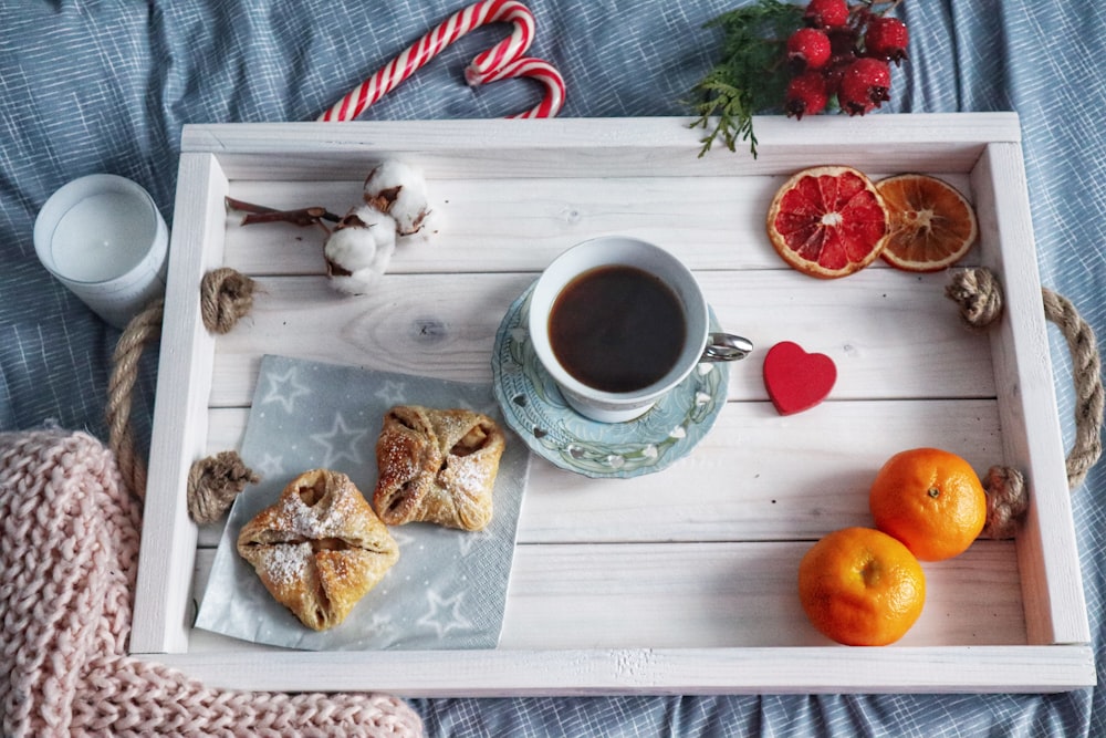 orange fruits and coffee mug on saucer on white tray