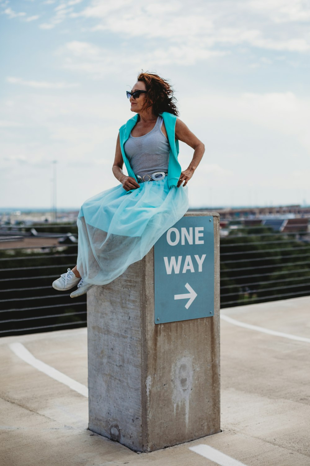 woman sitting on One Way sign stand