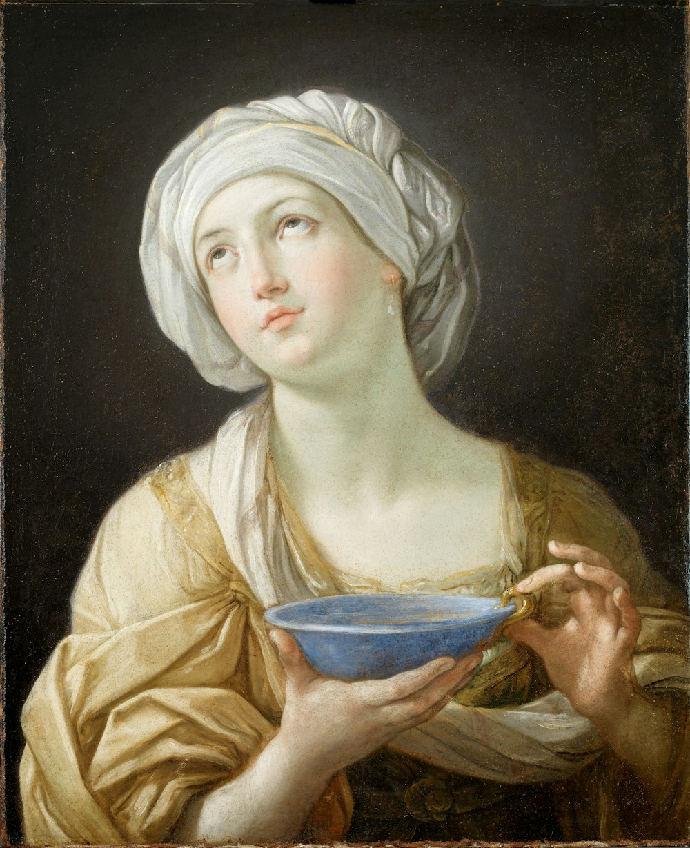 Frau mit weißem Kopfschmuck, während sie blaues Schüsselgemälde hält