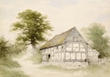 A rustic, half-timbered cottage set in a tranquil rural landscape. The cottage features exposed wooden beams and a sloped, shingled roof. Nearby, a large, leafy tree offers shade, and a dirt path winds past the front of the house. The surroundings are lush with greenery, indicative of a peaceful countryside setting.