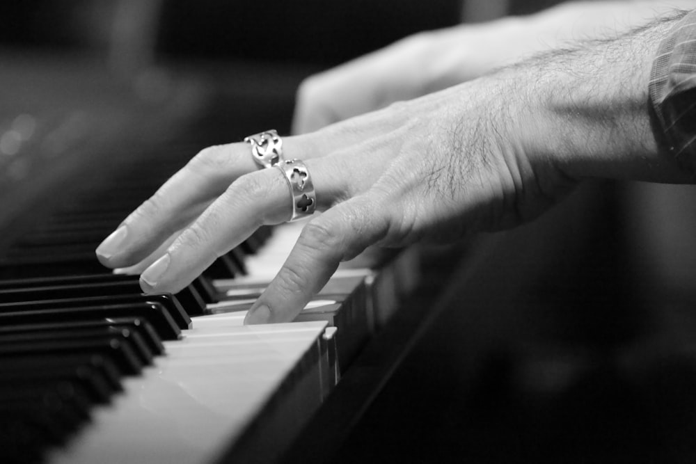 grayscale photo of person playing piano