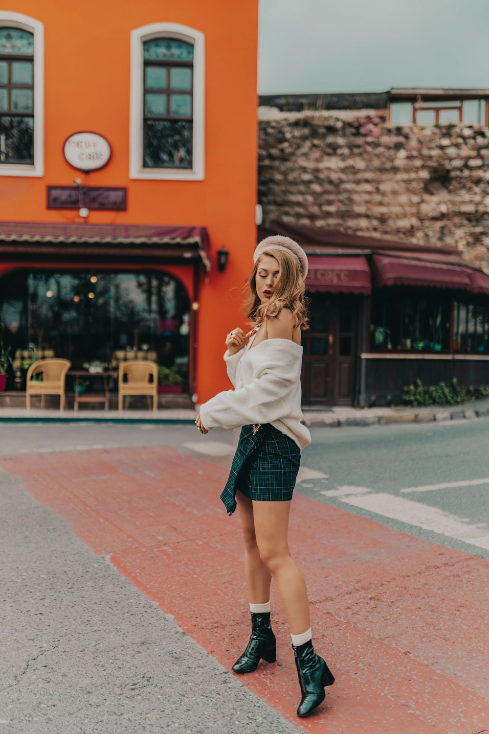 woman in white off-shoulder top, black mini skirt, and black leather shoes standing idle of street