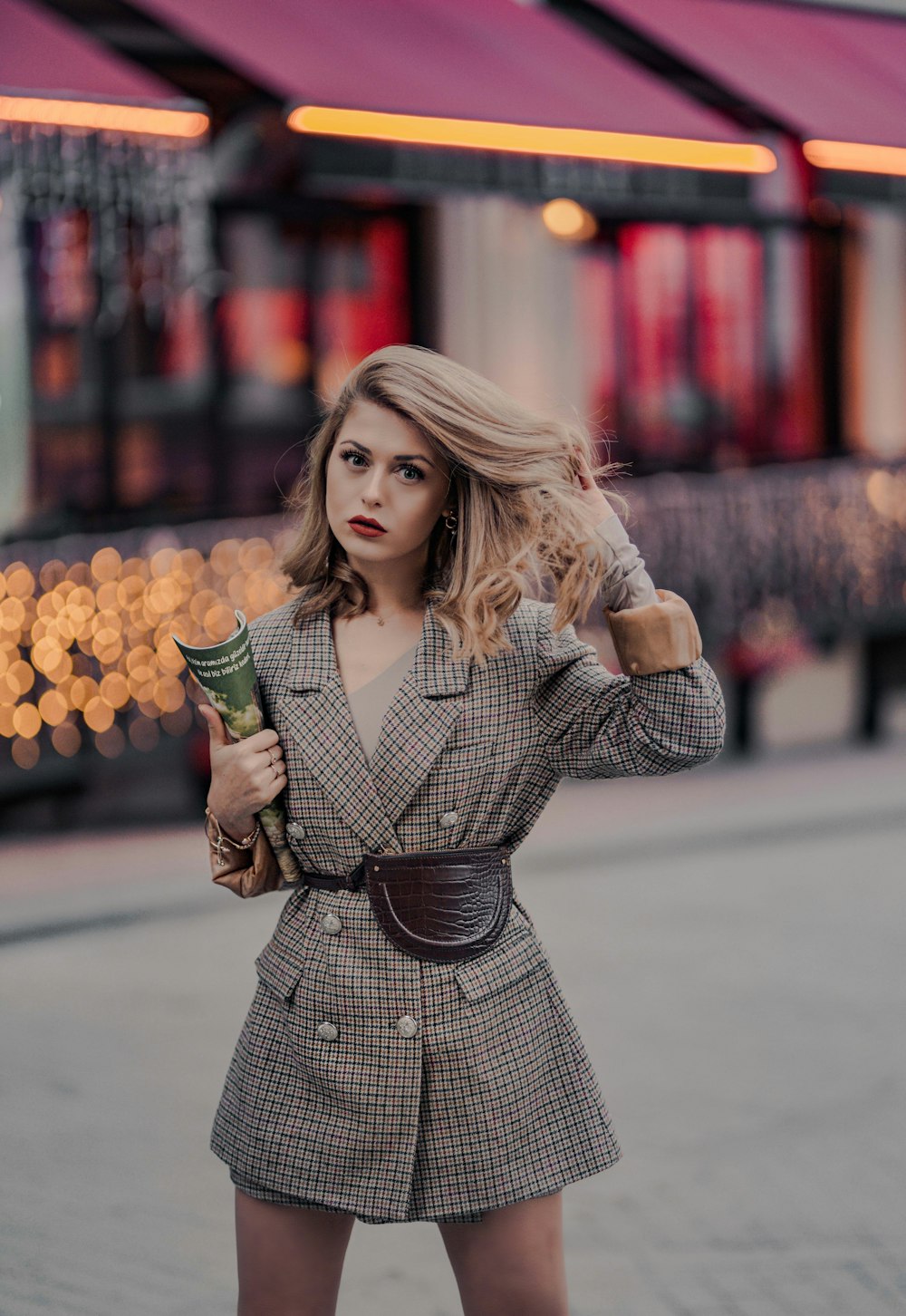 selective focus photography of girl standing near outdoor while holding her hair