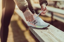 A happy customer lacing up fresh sneakers outdoors on a sunny day.