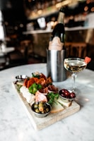 A smiling guest holding a charcuterie cup with a backdrop of the mobile cart and dancing script logo.