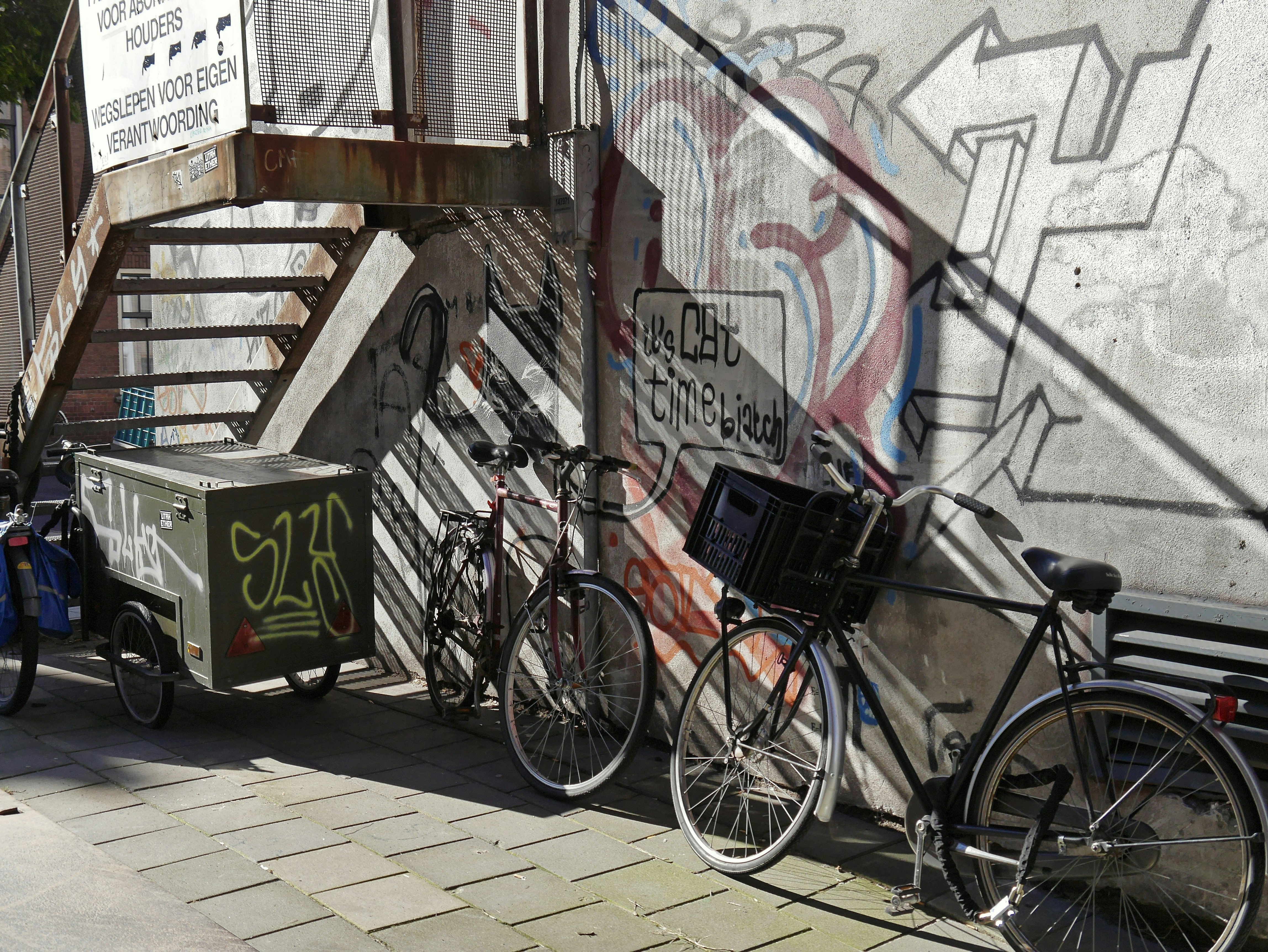 Photo of a street with a wall full of graffiti, wall paintings of a painted cat, parked bicycles and urban writings in Amsterdam city. This are building walls of old former fabrique halls, with sharp contrasts between sunlight and shadows. I like the spontaneous combination of all these images together, including the written texts on the walls. Free images of urban street photography by Fons Heijnsbroek, October 2016, The Netherlands.