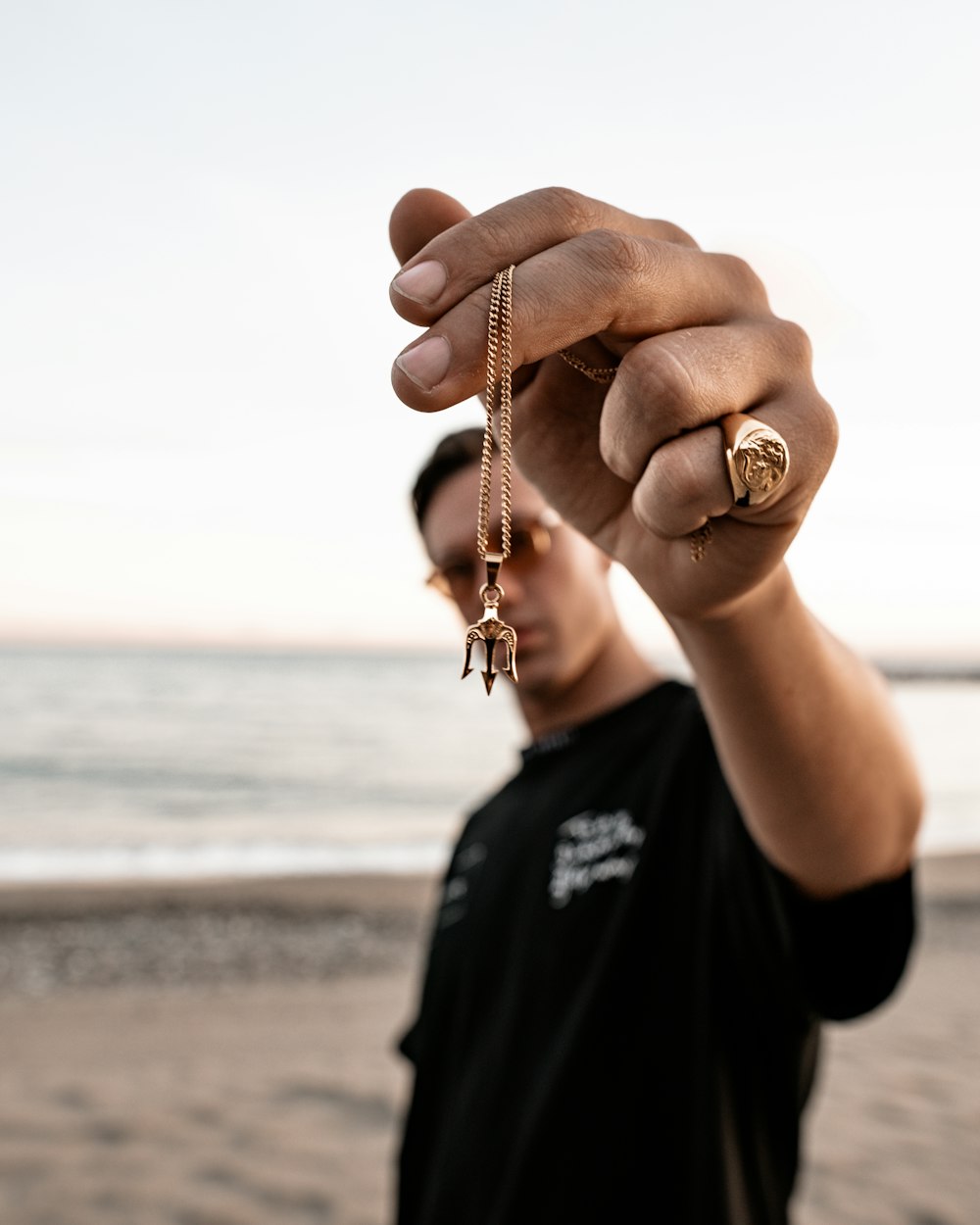 person holding gold-colored chain link necklace