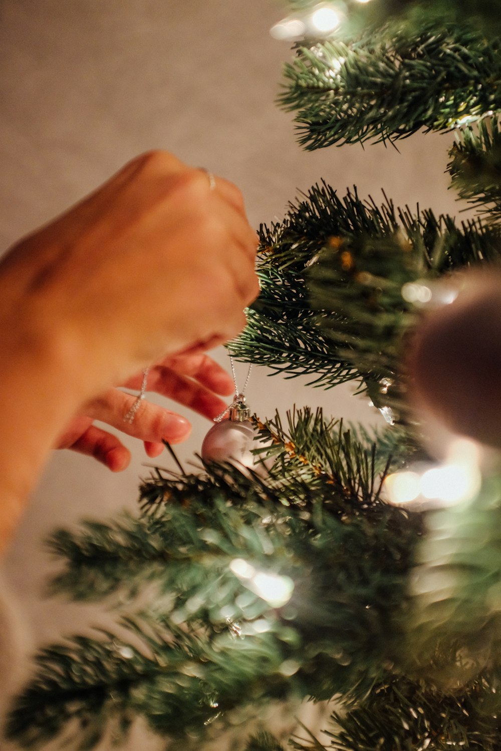 persona poniendo chuchería en el árbol de Navidad