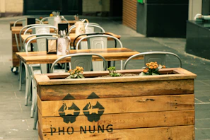 Outdoor seating area by the Alte Donau with wooden tables and green plants.