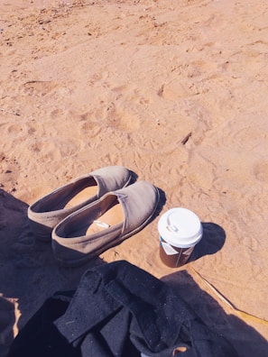Casual canvas shoes resting beside a coffee cup on a cozy table.