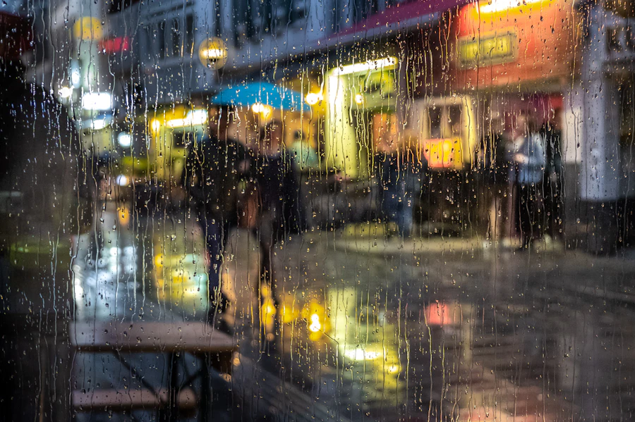 People on a rainy street seen through wet glass