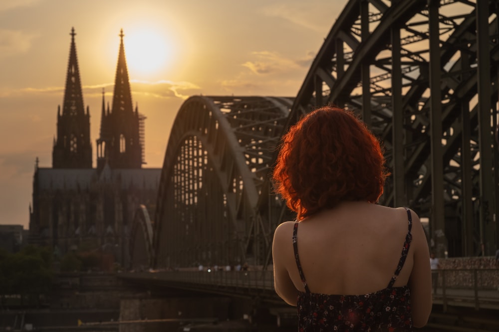 donna che indossa la parte superiore nera e multicolore della cinghia sottile in piedi mentre si affaccia all'indietro vicino alla cattedrale di Colonia in Germania