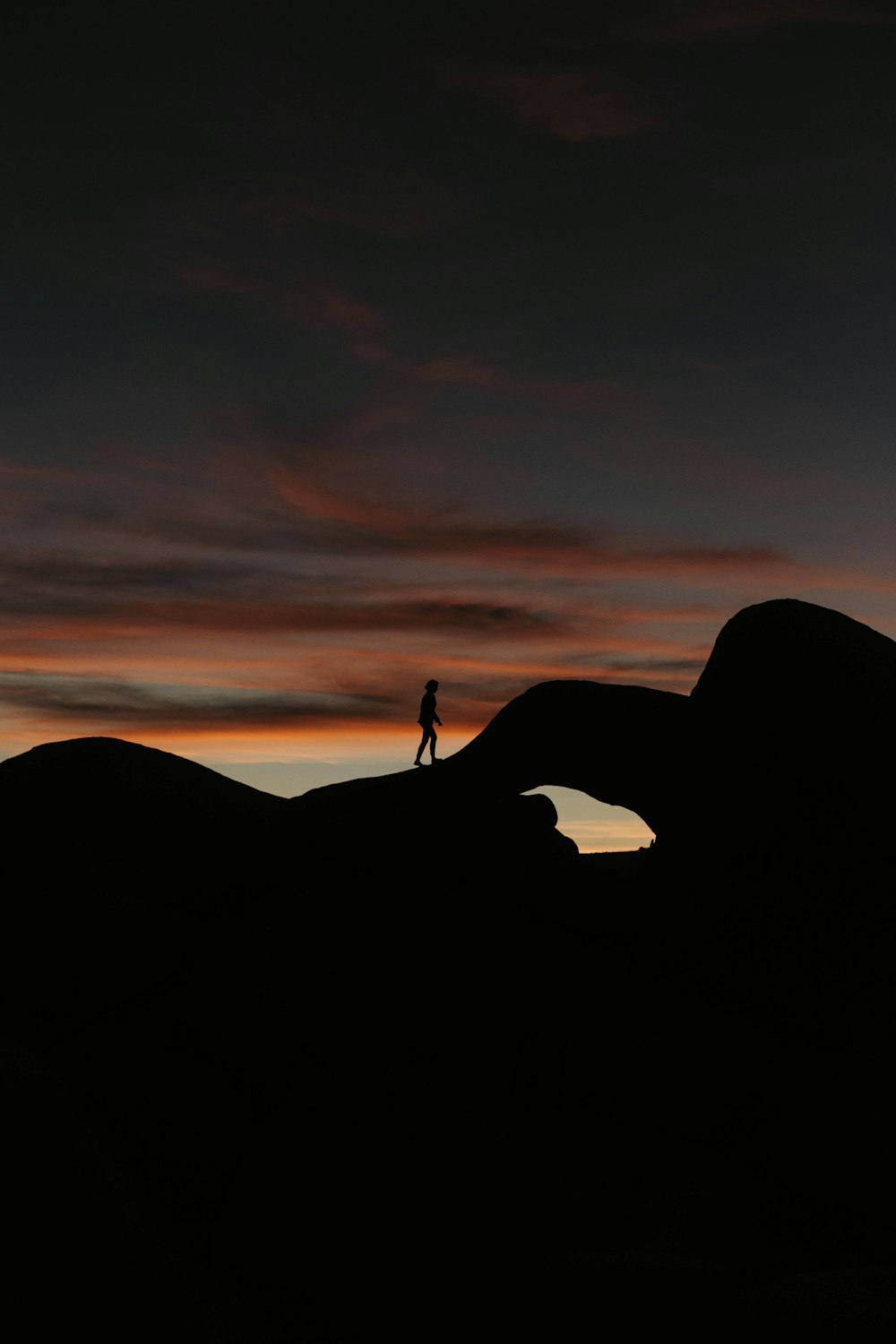 a person standing on top of a hill at sunset