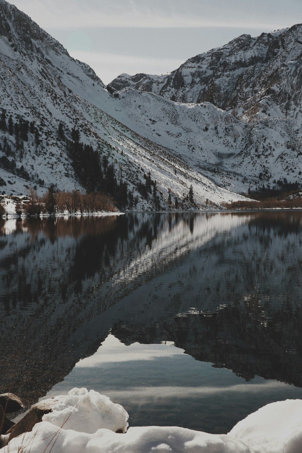 낮 동안 호수와 눈 덮인 산의 사진