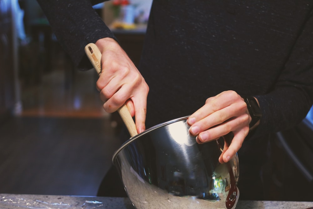 a person stirring a pot with a wooden spoon