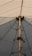 A geometric structure with a central pole surrounded by tension cables, supporting a large fabric canopy that forms a pointed shape with triangular sections.