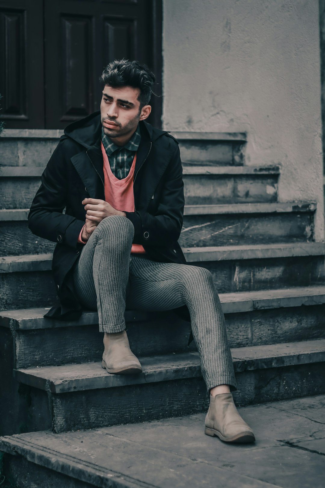 man in black coat sitting on staircase