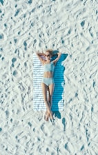 woman lying on sand with towel during daytime