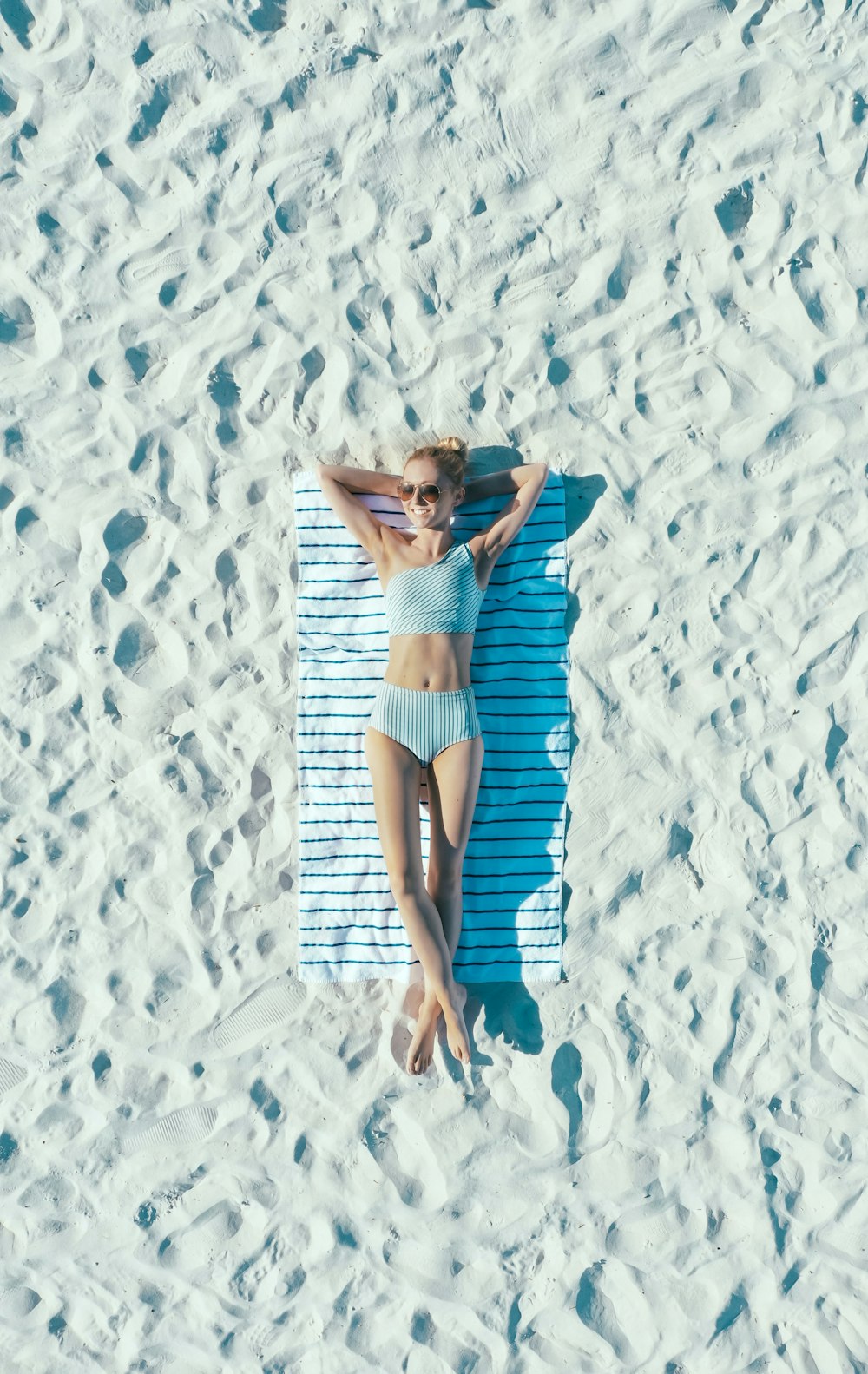 mulher deitada na areia com toalha durante o dia