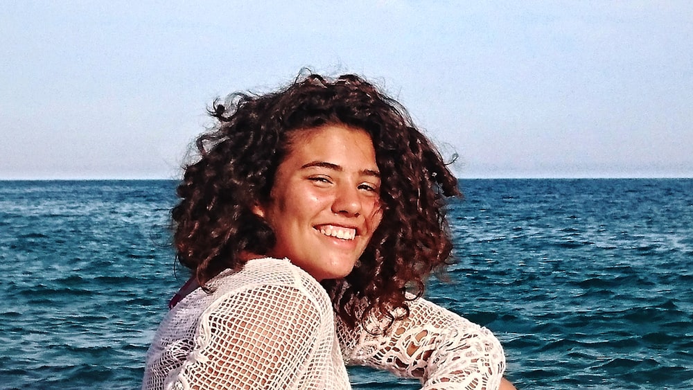 woman smiling at the ocean during day