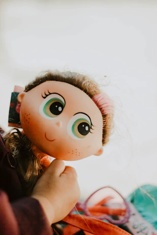Close-up of a smiling customer holding a beautifully crafted doll from Matilda Estetika in a bright, welcoming room.