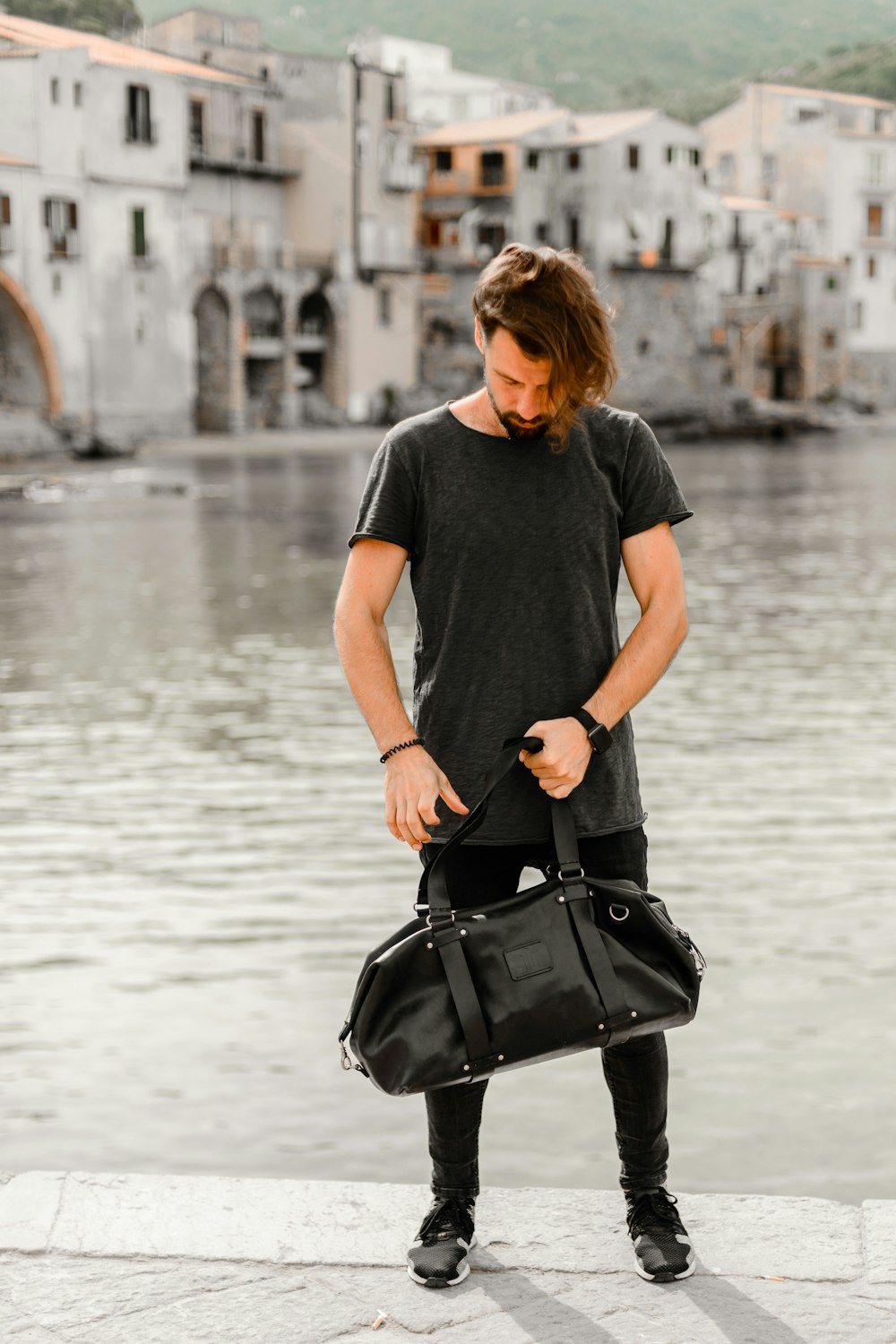 man standing on pier carrying bag during day