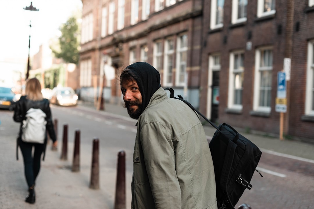 man in gray jacket walking on sidewalk