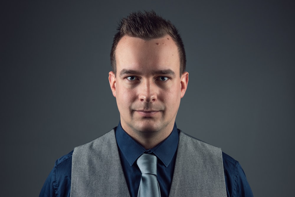 man wearing blue dress shirt and gray waistcoat