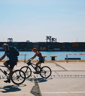 two people cycling near body of water during daytime