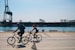 two people cycling near body of water during daytime