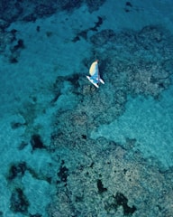 An aerial view of a yacht navigating through crystal-clear waters.