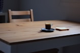 A minimalist plate with a slice of pizza and a small cup of espresso on a clean white table.