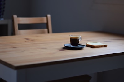 A minimalist plate with a slice of pizza and a small cup of espresso on a clean white table.