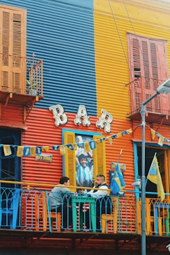 two men sitting outside of bar near table chatting