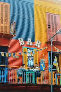 two men sitting outside of bar near table chatting