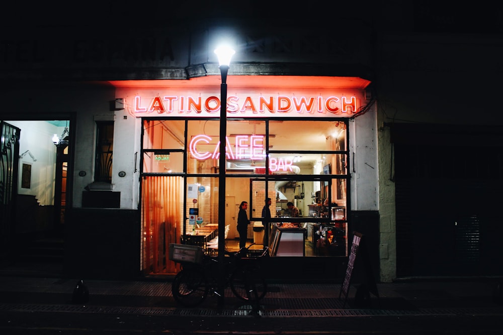 black bike outside Latino Sandwich building and few people inside during night time