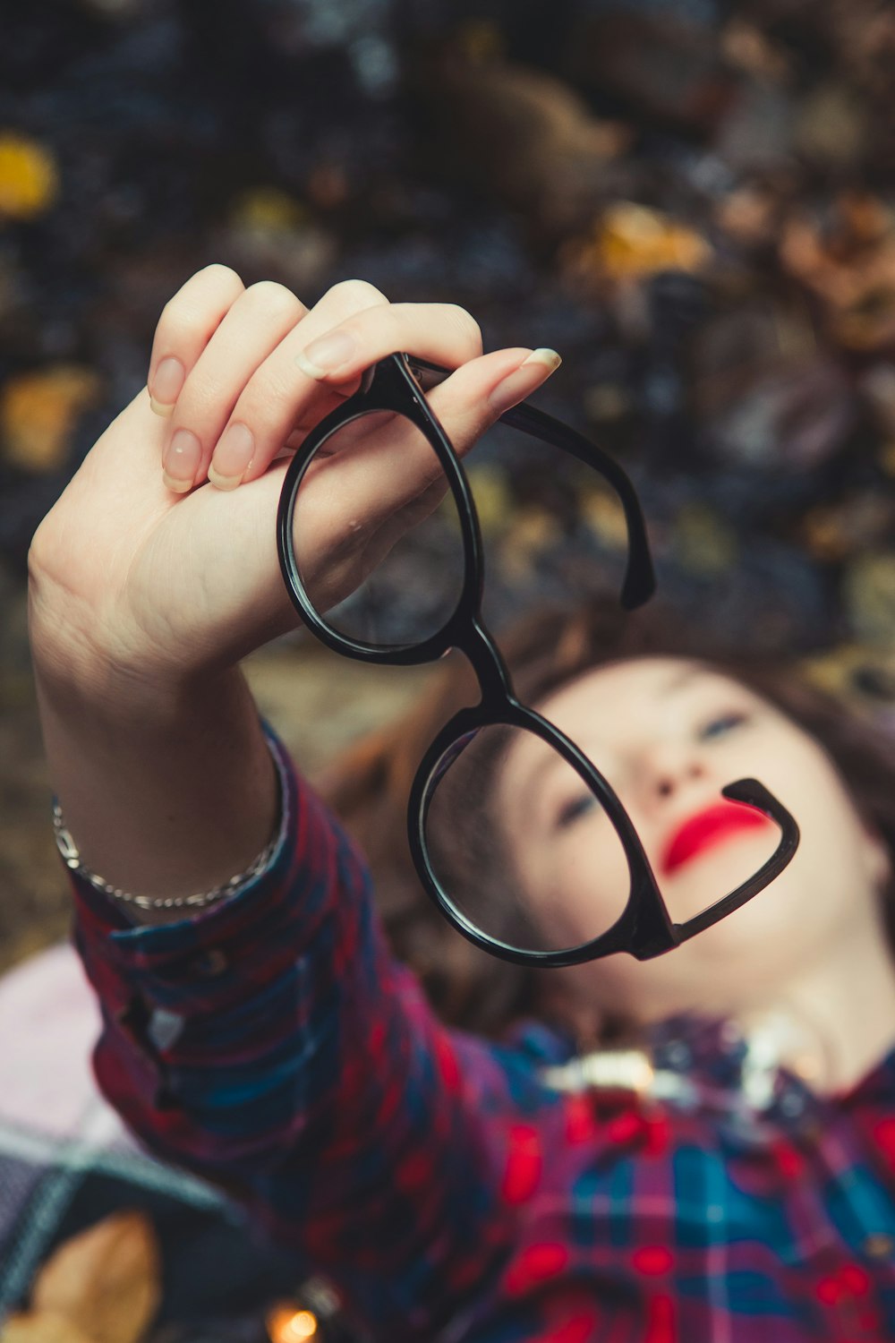 woman holding black-framed eyeglasses