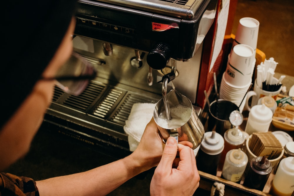 person putting coffee on mug