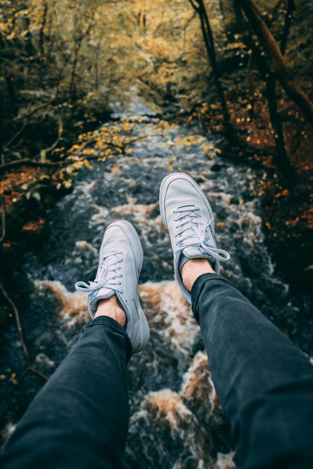 a person standing in front of a river in the woods